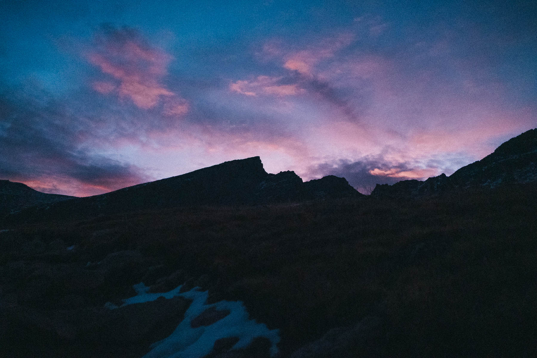 Purple and pink sunset behind mountain silhouettes